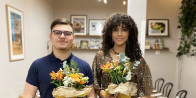 Nicole och Henry, guldmedaljörer i gymnasie sm håller i blommor och tittar in i kameran.