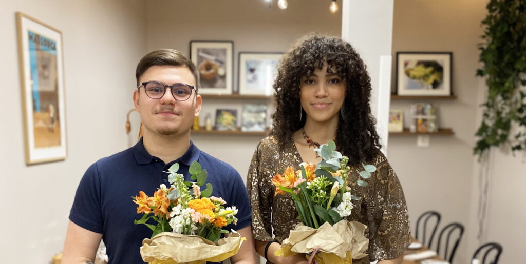 Nicole och Henry, guldmedaljörer i gymnasie sm håller i blommor och tittar in i kameran.