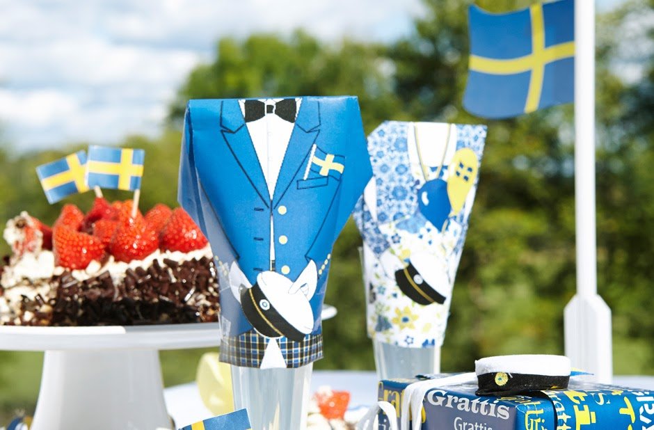 Ett bord med jordgubbstårta, flagga, paket och studentdekorationer.