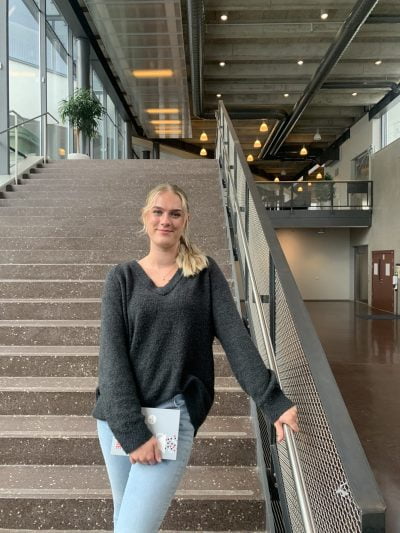 Maja Svärd står leende i en trappa och håller i ett anteckningsblock.