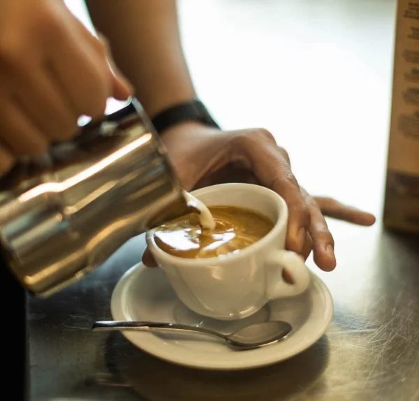 Skummad mjölk hälls upp i en liten espressokopp.