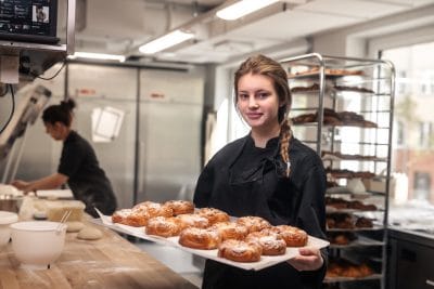 Bagerielev håller en plåt med bakverk.
