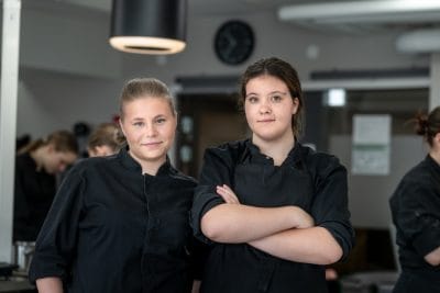 Två tjejer i konditoriet ser in i kameran.