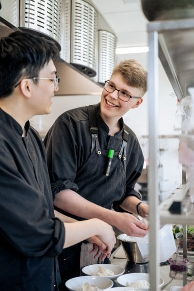 Två killar i köket samarbetar med matlagningen.