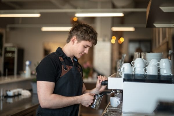 Killar ångar mjölk till en kaffe.