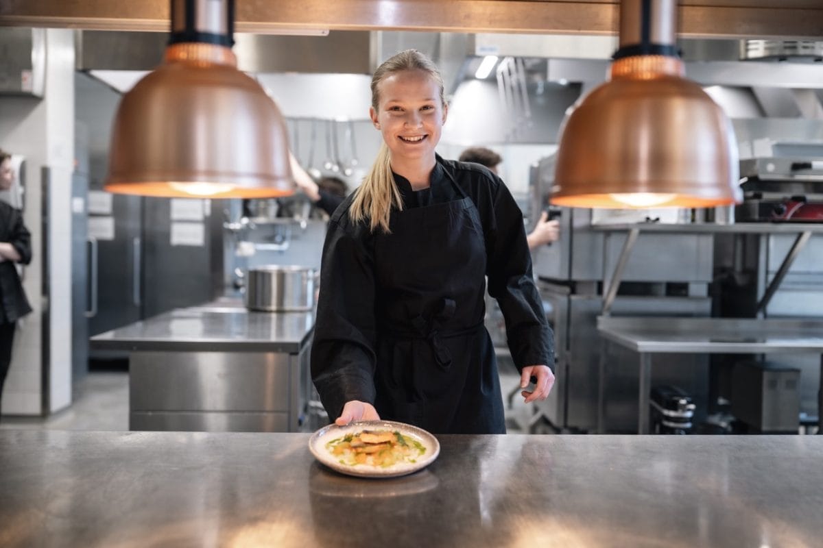 Tjej serverar en färdig rätt från köksluckan.